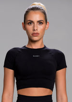A model wears the Sassy Sportswear Crop Top Timeless in the Black Addicted color